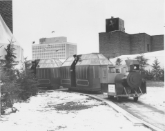 The train running around the snowy roof, with figures inside behind the windows. [Hudson's Bay Company Archives, HBCA 1987-363-E-610 - 51]